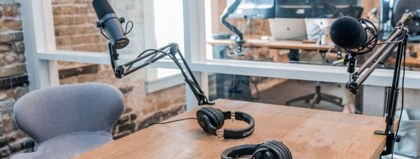 A recording studio featuring two microphones and a pair of headphones on a table.