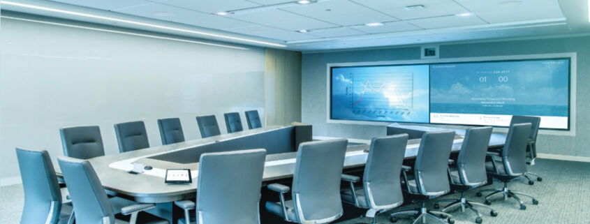 A modern collaboration space with a U-shaped table, multiple displays, and an advanced videoconferencing setup.