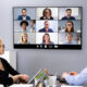 An office with four in-person employees video conferencing with remote employees.