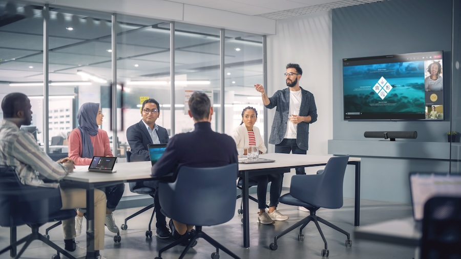 A group of new employees in a corporate training room during a video call.