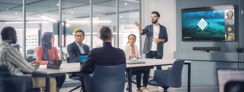 A group of new employees in a corporate training room during a video call.