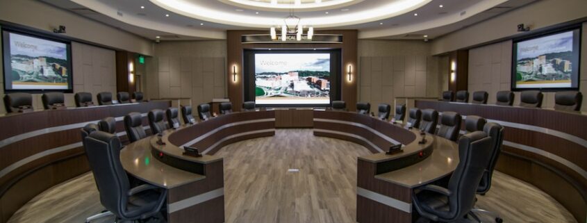 A large conference room featuring an elaborate AV system with multiple screens.