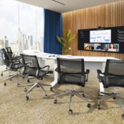 A large conference room with a semi-circle table, chairs, and video display on the board.